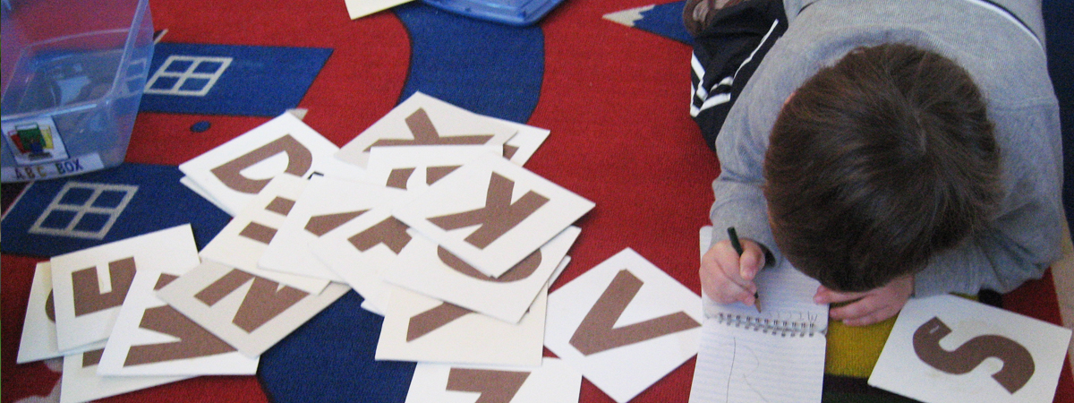 Todler at play with notepad on the colorful carpet.